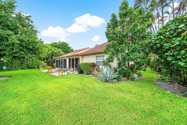 a view of a house with a big yard potted plants and large tree