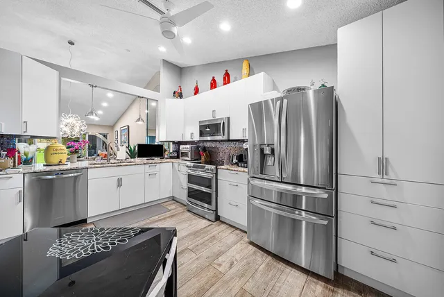 a kitchen with a refrigerator and white cabinets