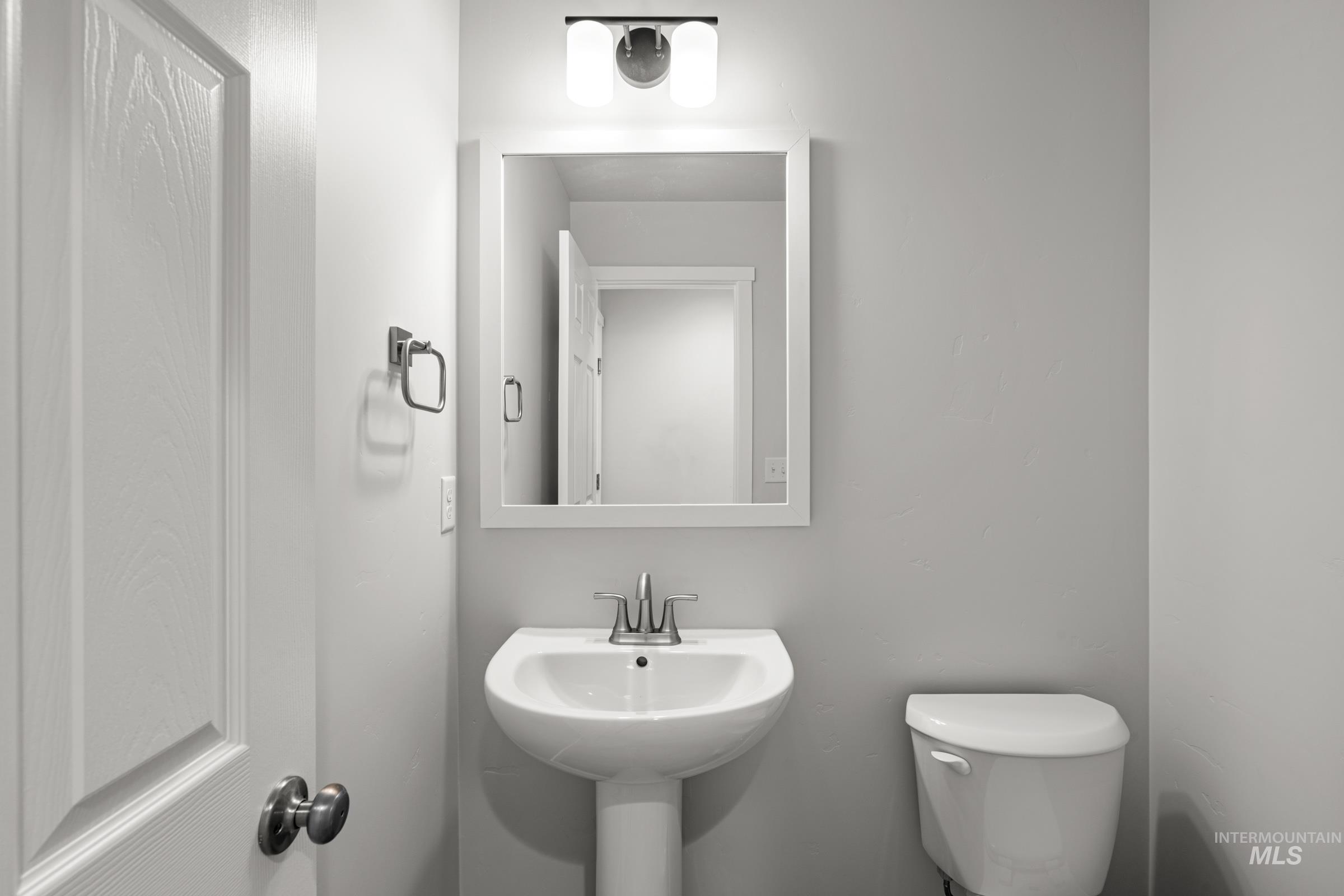 14056 Shiny Spruce Street Caldwell, ID 83607 - Photo 25 of 25 Bathroom featuring a pedestal sink with chrome faucet, framed mirror, and contemporary wall sconce lighting