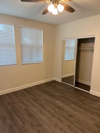 an empty room with wooden floor and windows