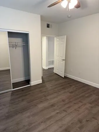 an empty room with wooden floor chandelier fan and windows