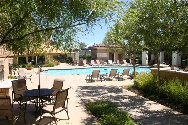 a view of a patio with table and chairs and potted plants and large trees