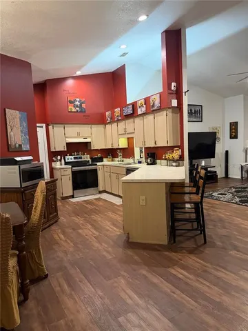a kitchen with a stove a refrigerator and chairs