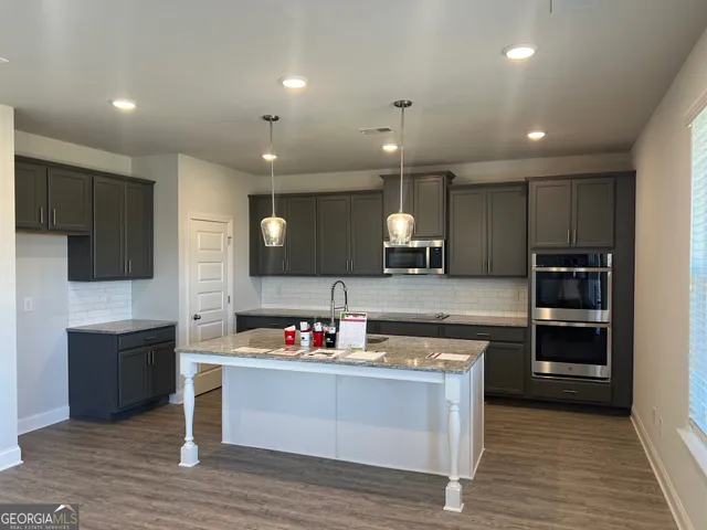 a kitchen with granite countertop a sink cabinets and stainless steel appliances