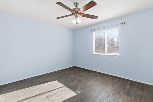 an empty room with a window and a ceiling fan