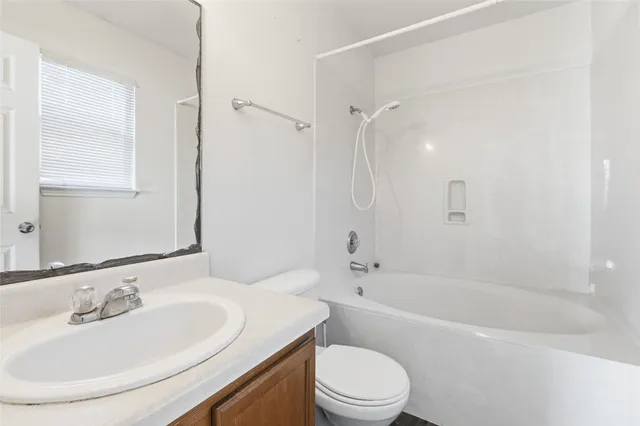 a bathroom with a bathtub shower sink vanity mirror and toilet