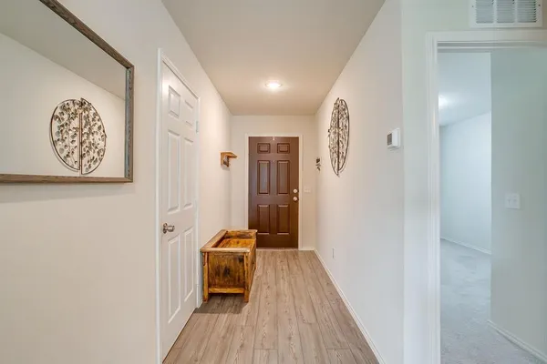 a view of a hallway with wooden floor and a bathroom