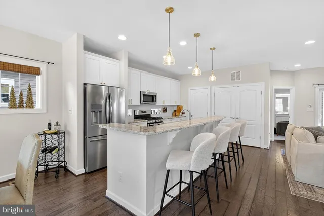 a kitchen with stainless steel appliances a dining table chairs refrigerator and microwave