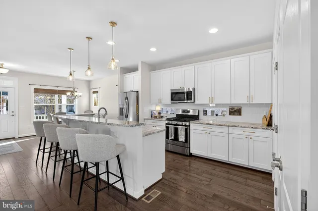 a kitchen with stainless steel appliances kitchen island granite countertop a stove a sink a dining table and chairs