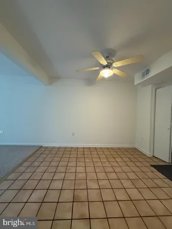 a view of an empty room and chandelier fan