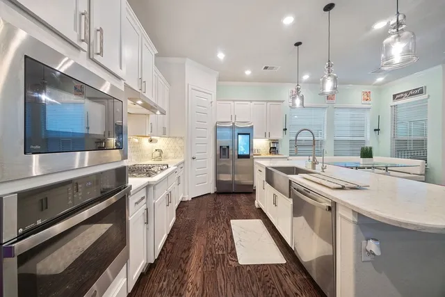 a large kitchen with kitchen island a stove a sink a center island and wooden floor