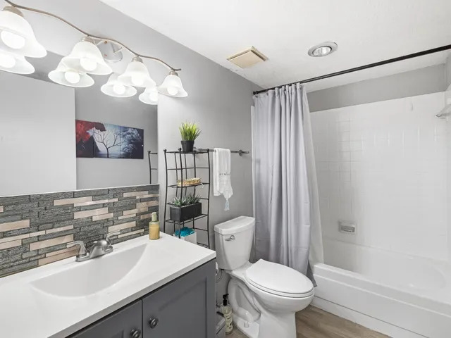 a bathroom with a sink a toilet a mirror a vanity and shower