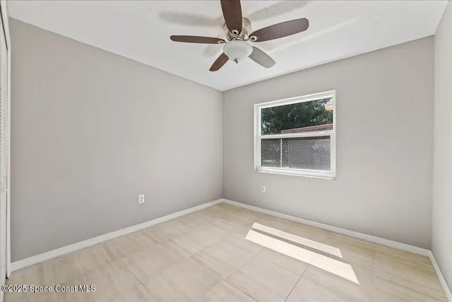 an empty room with windows and ceiling fan