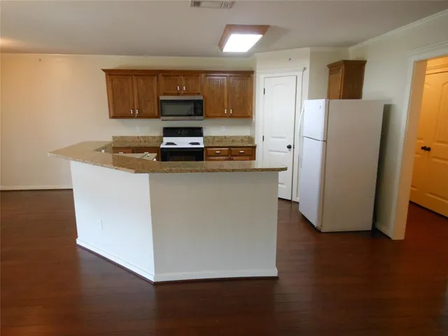 a kitchen with stainless steel appliances granite countertop a refrigerator a stove a sink and a microwave