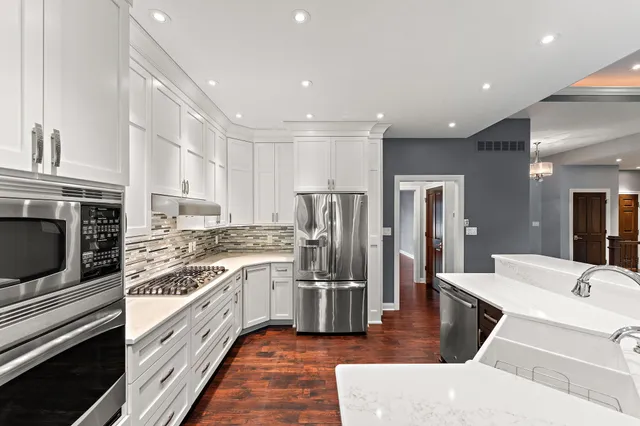 a large white kitchen with stainless steel appliances granite countertop a stove and a refrigerator
