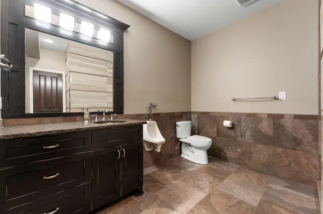 a bathroom with a granite countertop toilet a sink and a mirror
