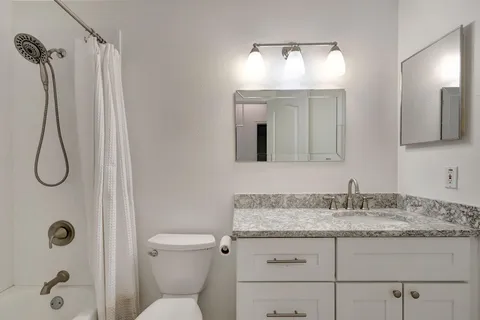 a bathroom with a granite countertop sink toilet and shower