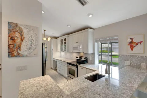 a kitchen with granite countertop a stove a sink and a refrigerator