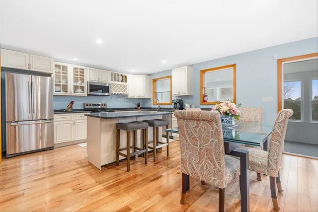 a kitchen with stainless steel appliances kitchen island granite countertop a refrigerator a stove a kitchen island with chairs and wooden floor