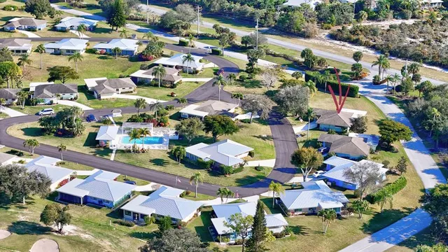 a view of a white house with a big yard and potted plants and large trees