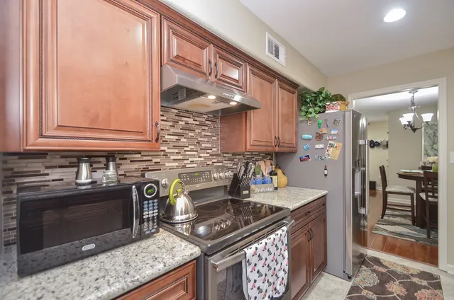a kitchen with stainless steel appliances granite countertop a stove a sink and a microwave