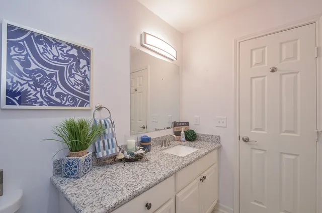 a bathroom with a granite countertop toilet a sink and a mirror