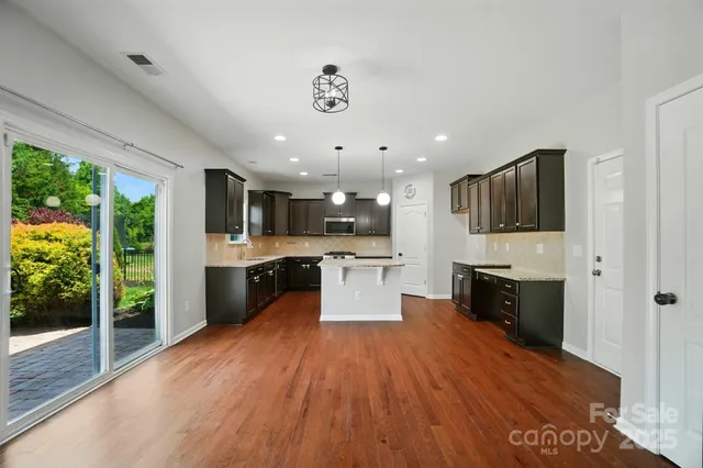 a large kitchen with stainless steel appliances granite countertop a large center island and a wooden floors