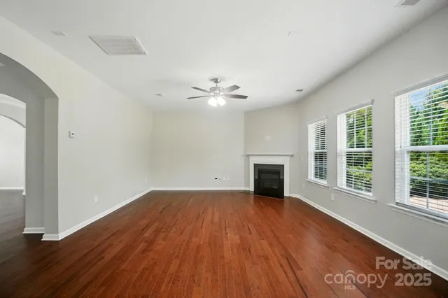 an empty room with wooden floor fireplace and windows