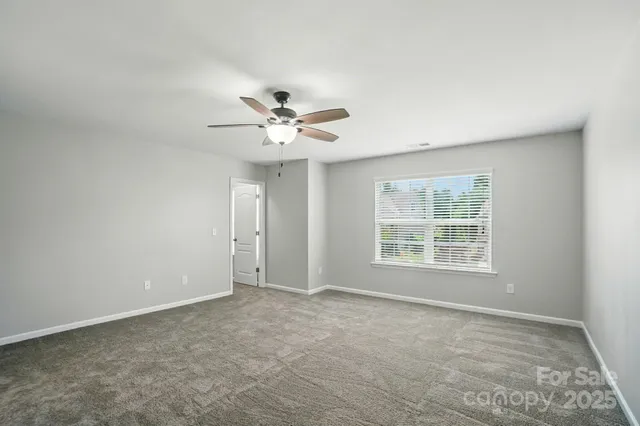 an empty room with a chandelier fan and windows