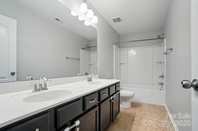 a bathroom with a double vanity sink toilet mirror and shower