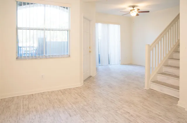 an empty room with wooden floor chandelier and windows