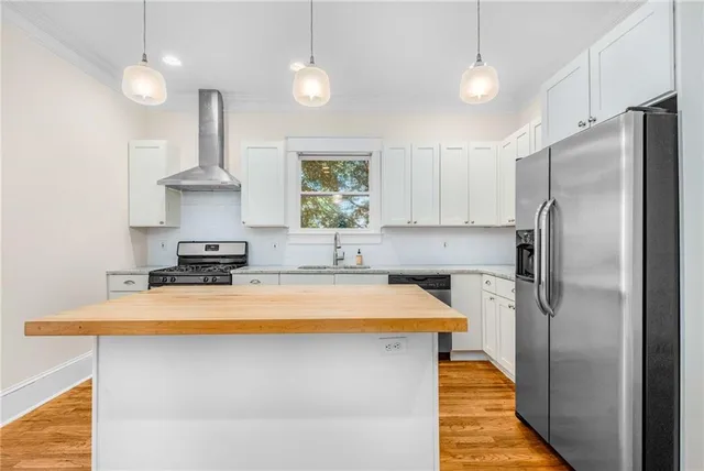 a kitchen with stainless steel appliances a sink a refrigerator a stove a chimney and a center island