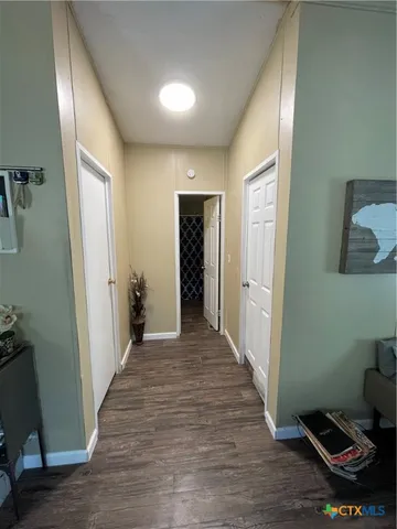 a view of a hallway with wooden floor and a bathroom