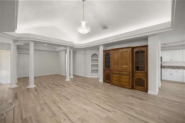 a kitchen with granite countertop a stove a sink and white cabinets with wooden floor next to windows