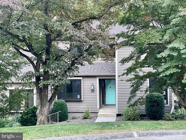 a front view of a house with a garden and tree