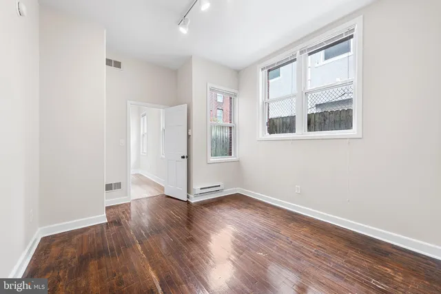 a view of an empty room with wooden floor and a window