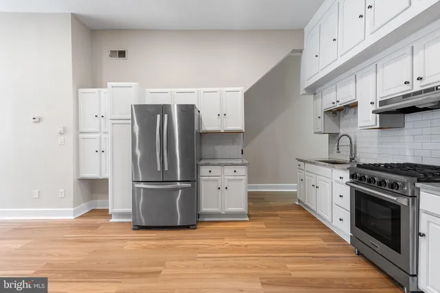 a kitchen with a stove a refrigerator and a wooden floor