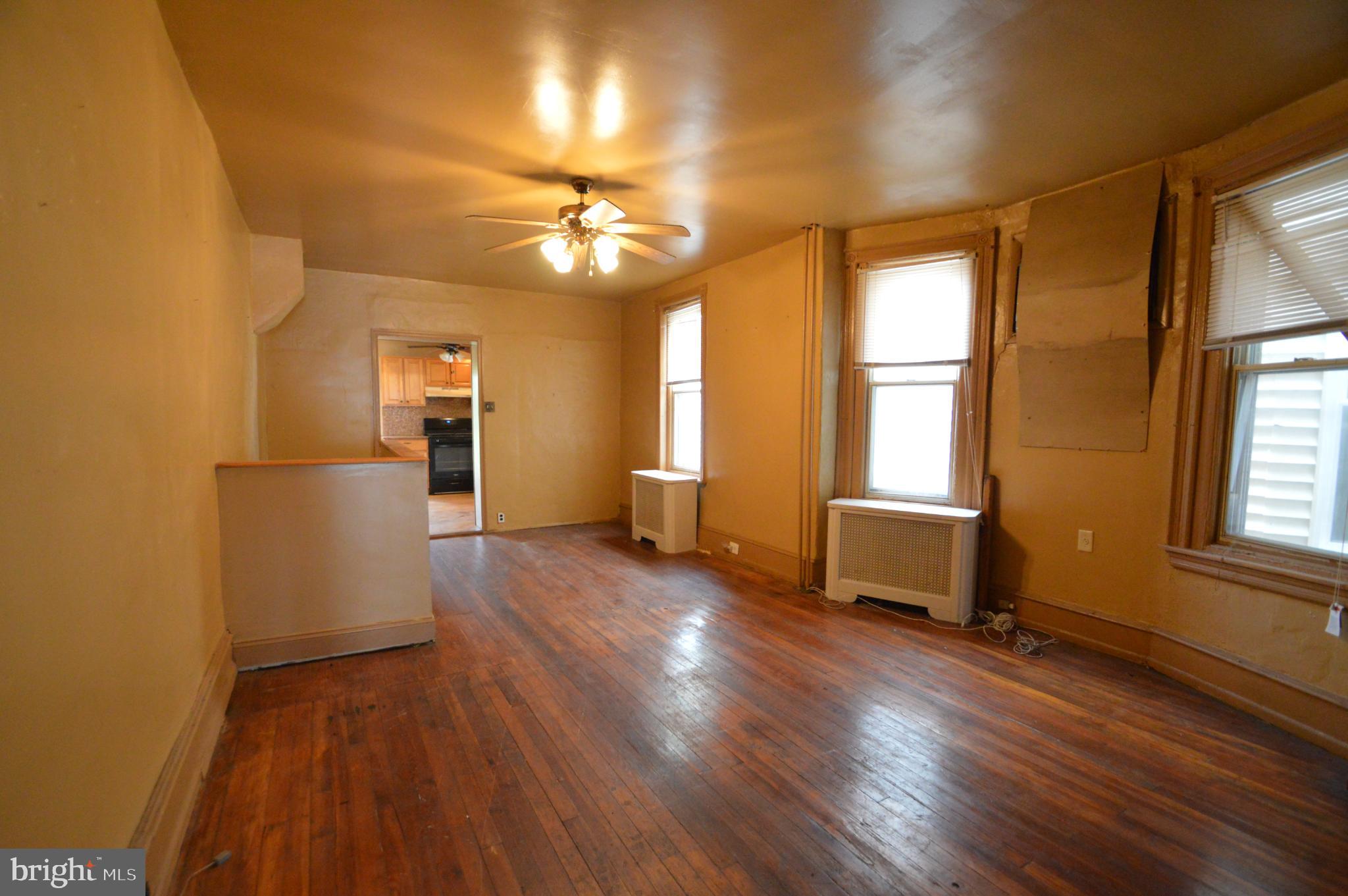 6011 Sansom Street Philadelphia, PA 19139 - Photo 6 of 24 a view of a livingroom with furniture hardwood floor a ceiling fan and windows