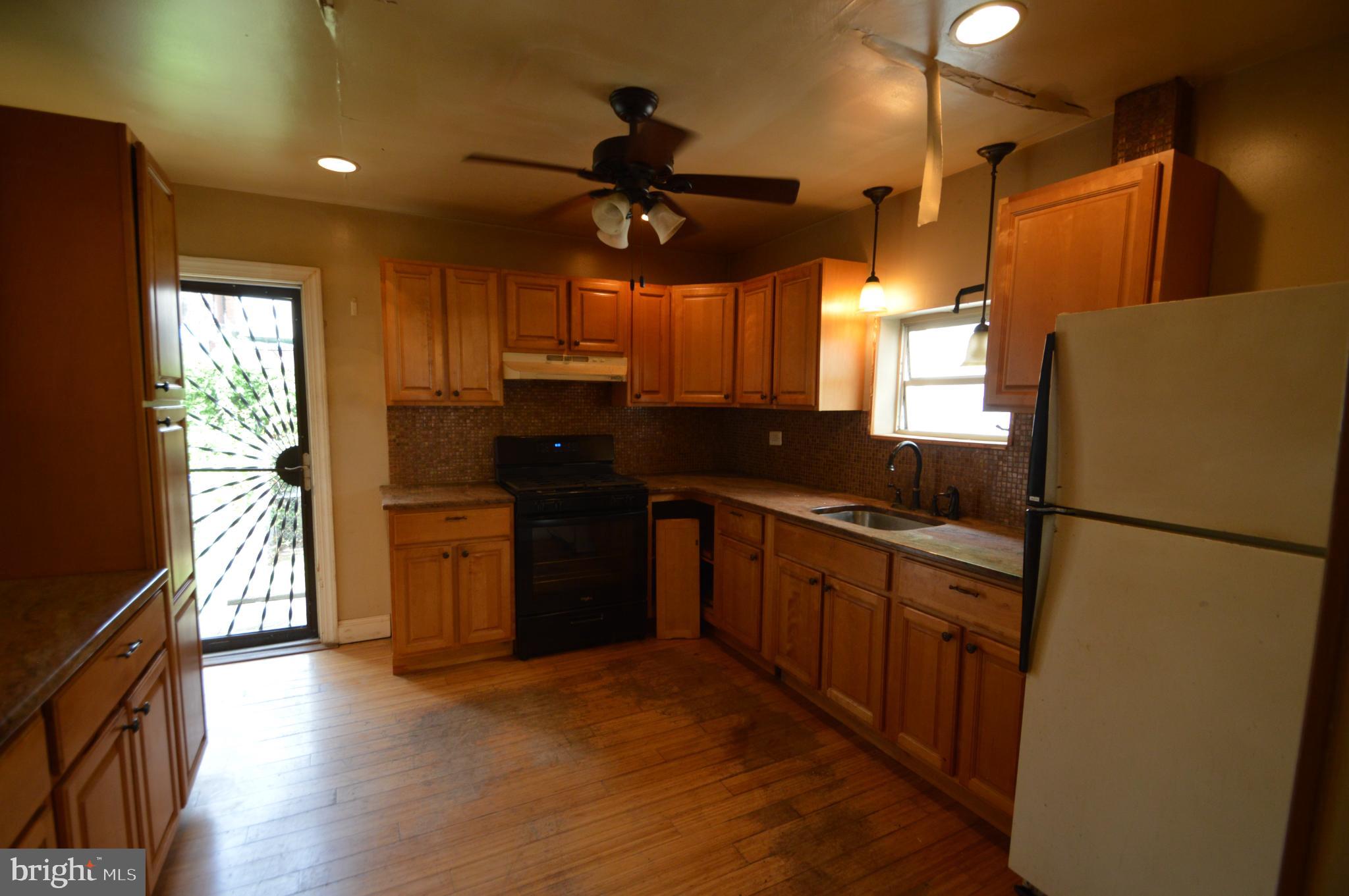 6011 Sansom Street Philadelphia, PA 19139 - Photo 10 of 24 a kitchen with stainless steel appliances granite countertop a refrigerator a sink dishwasher a stove and a dining table with wooden floor