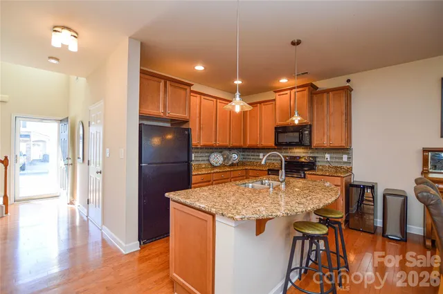a kitchen with stainless steel appliances granite countertop a refrigerator a stove top oven and a sink
