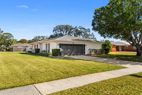 a front view of a house with a garden and tree