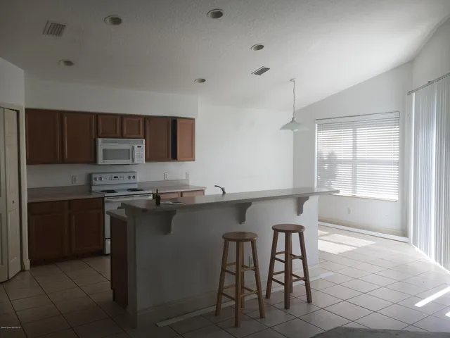 a kitchen with stainless steel appliances a table chairs refrigerator and microwave