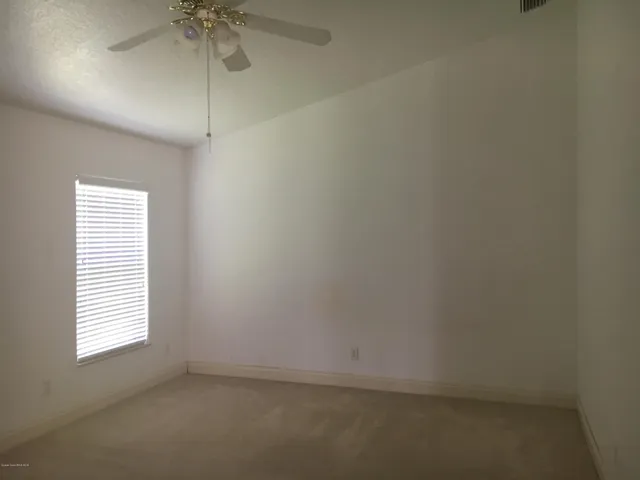 an empty room with a window and a fan