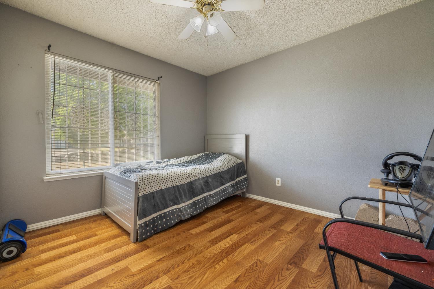 808 Cadillac Drive Modesto, CA 95351 - Photo 20 of 41 Bedroom featuring a textured ceiling, wood finished laminate floors, and a ceiling fan