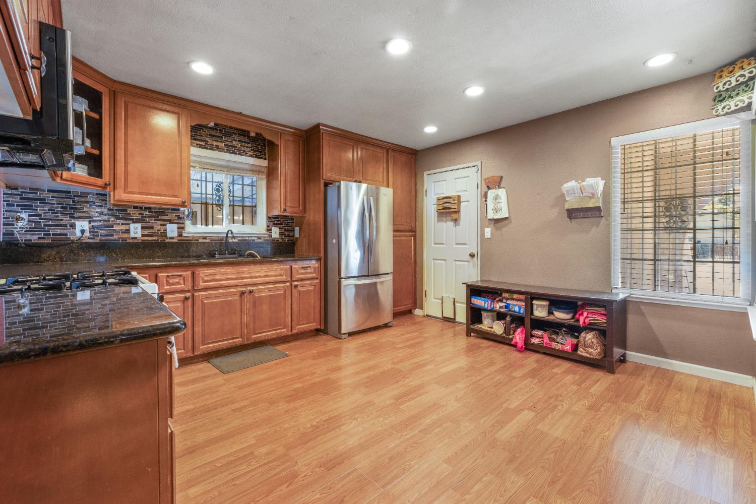 808 Cadillac Drive Modesto, CA 95351 - Photo 6 of 41 kitchen featuring wood finish cabinetry, dark stone counters, light- laminate flooring, and recessed lighting