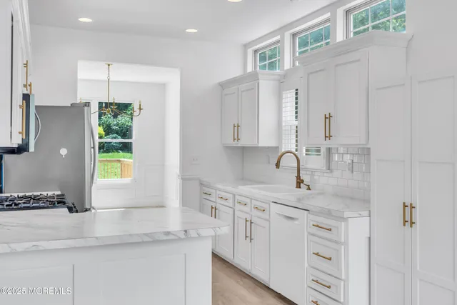 a kitchen with stainless steel appliances granite countertop a sink a stove and a window