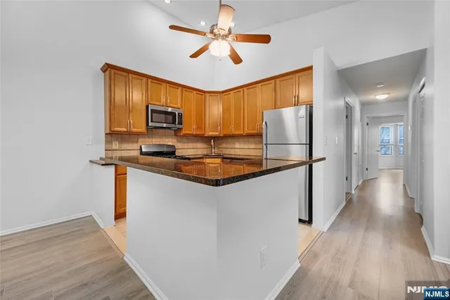 a kitchen with stainless steel appliances granite countertop a refrigerator a stove a sink and a microwave