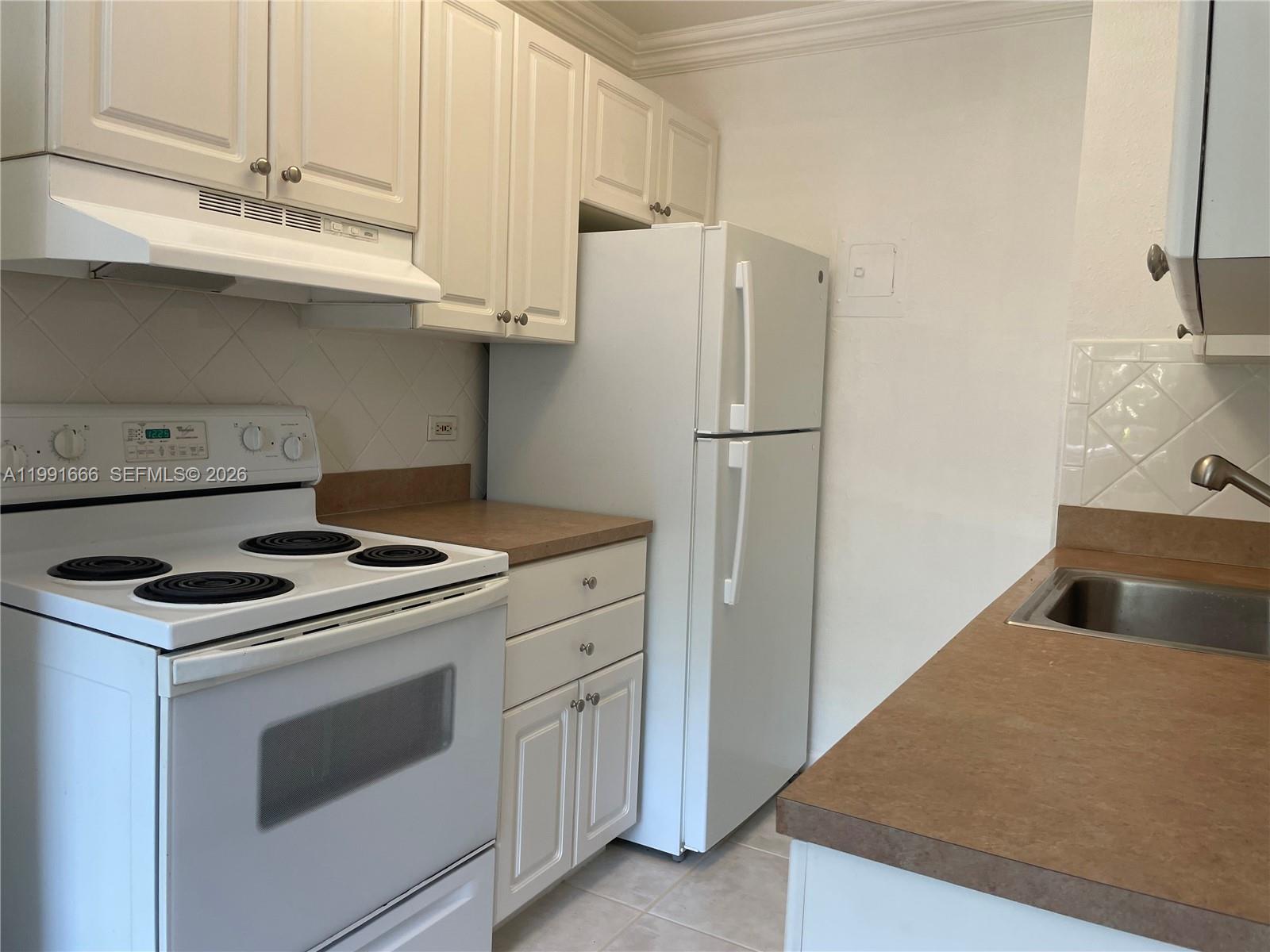 1405 Miami Road, Unit 23 Fort Lauderdale, FL 33316 - Photo 5 of 20 a kitchen with granite countertop white cabinets and refrigerator