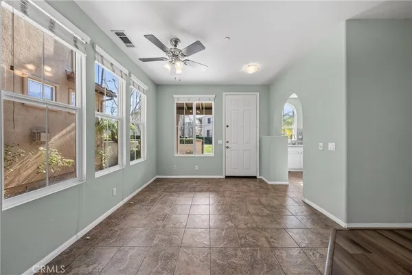 a view of an empty room with window and chandelier fan
