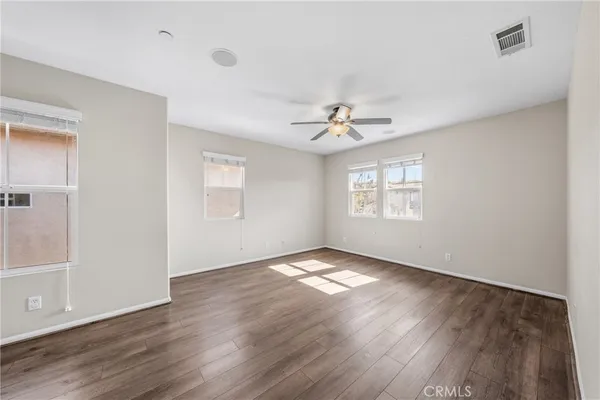 a view of an empty room with a window and wooden floor